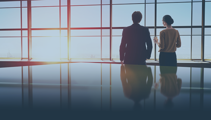 Business man and woman standing by a window