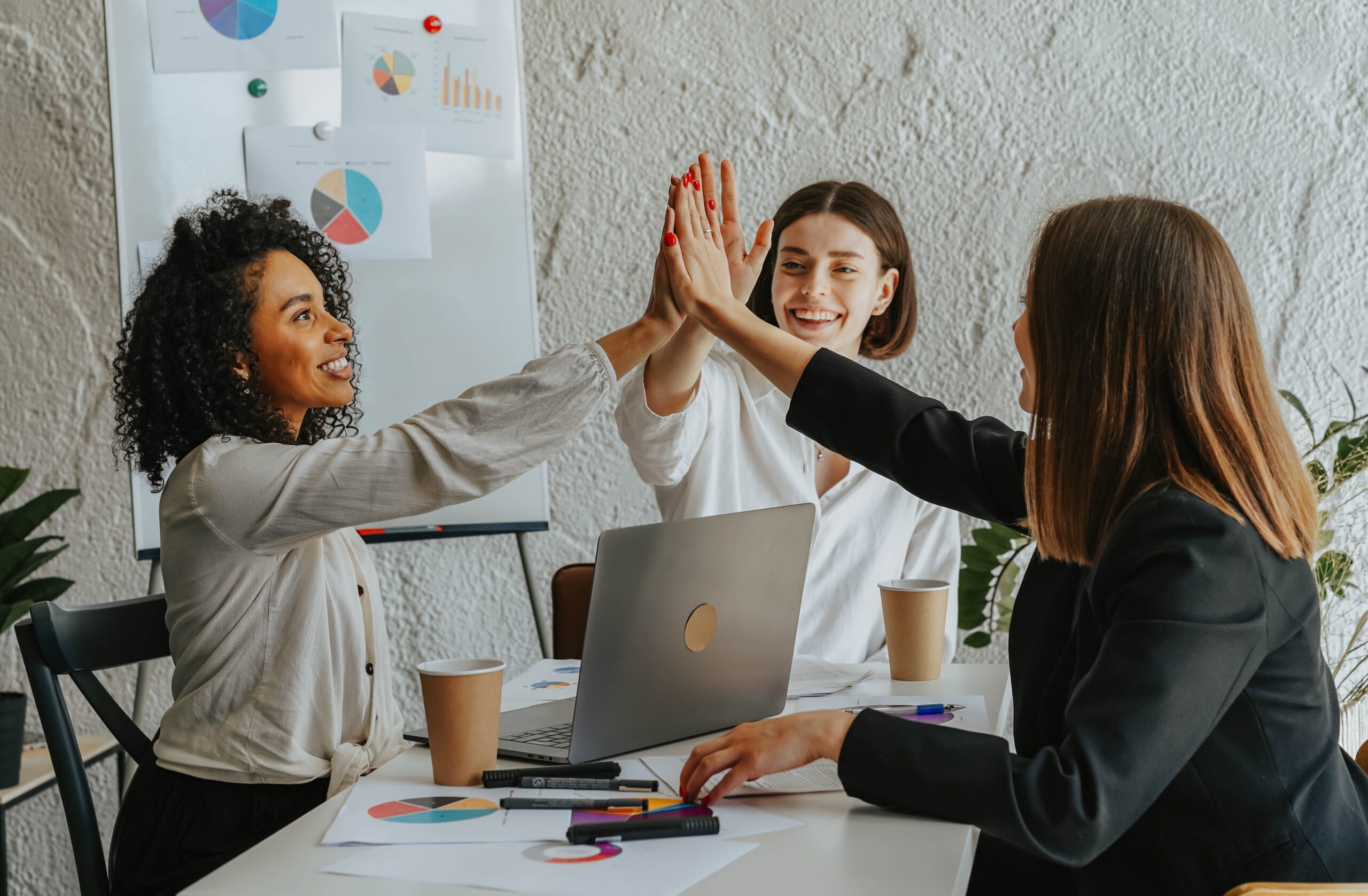 diverse business women in meeting working together and giving a high-five